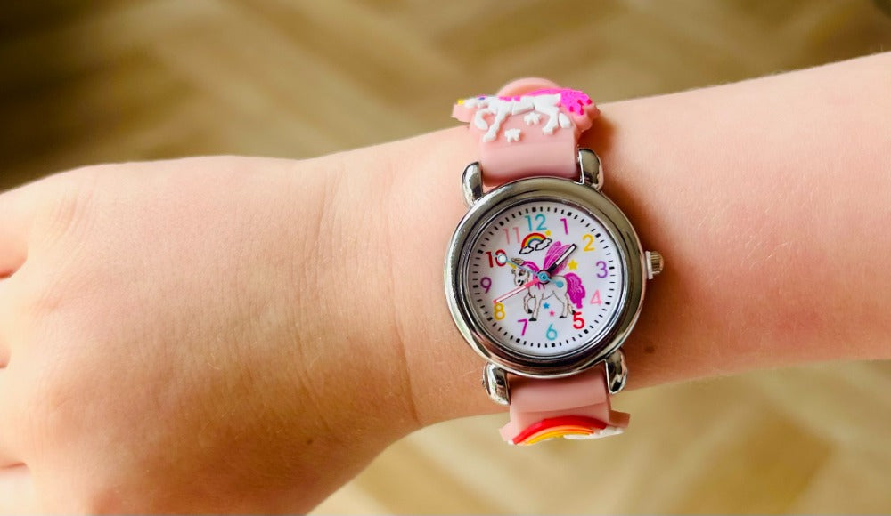 Children's watch with a colorful strap on a wrist against a blurred background