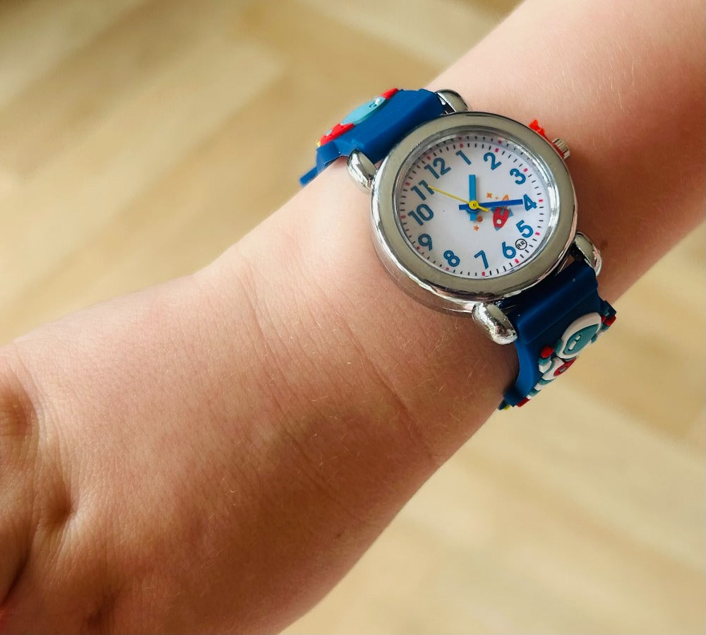 Child's wrist wearing a colorful watch with a blue strap on a wooden surface