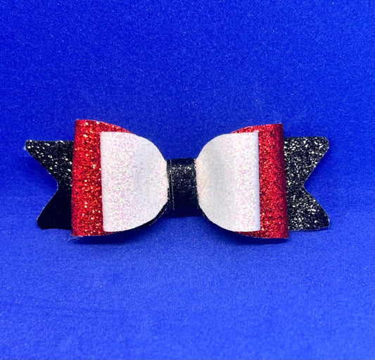 Bow-shaped hair accessory with red, white, and black glittery design on a blue background