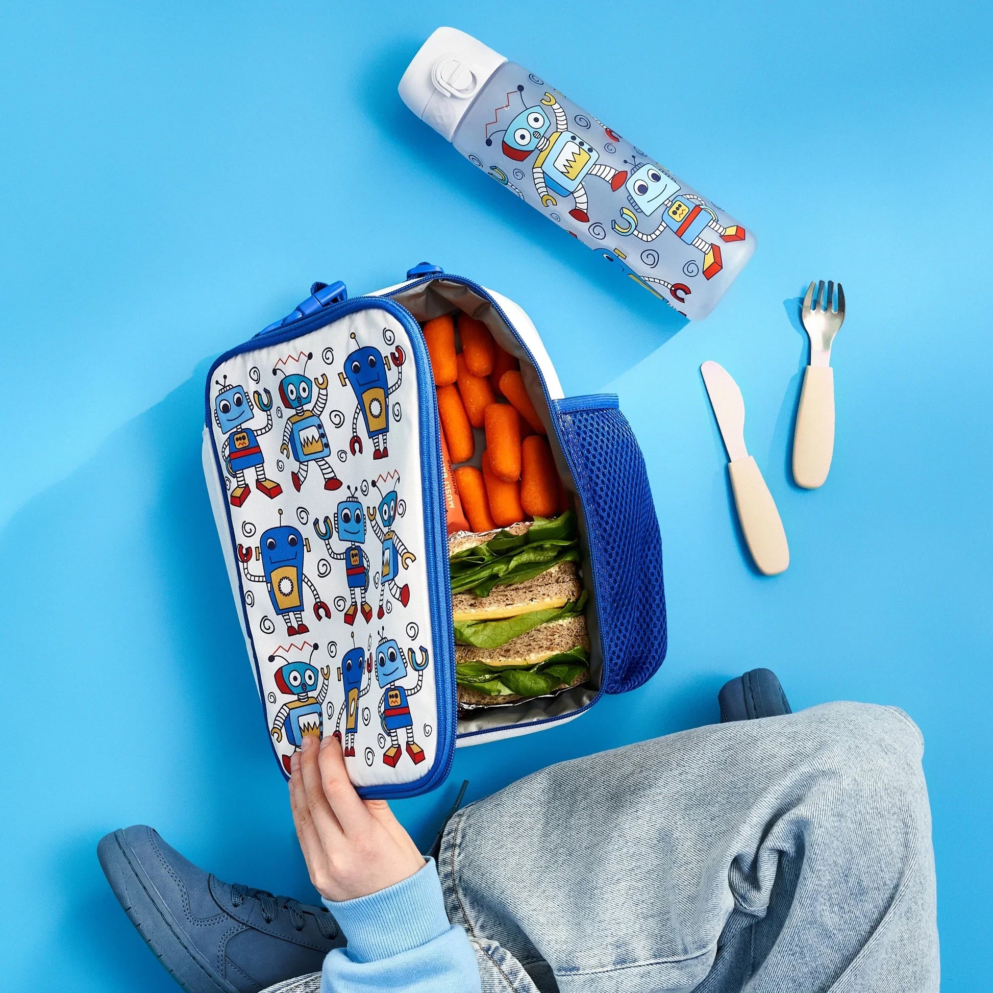 Lunchbox with robot design, filled with food, on a blue background