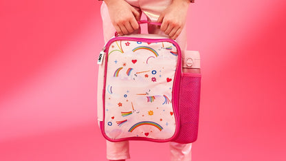 Child holding a pink lunch bag with rainbow and unicorn design on a pink background