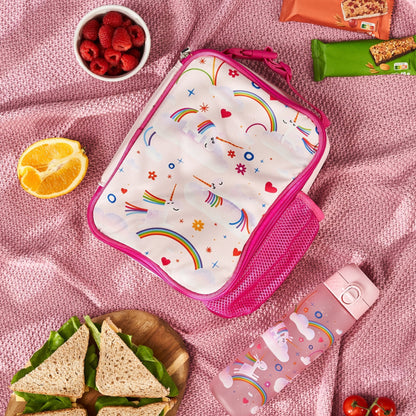 Lunch bag with unicorn and rainbow design on a pink blanket with snacks and sandwiches.