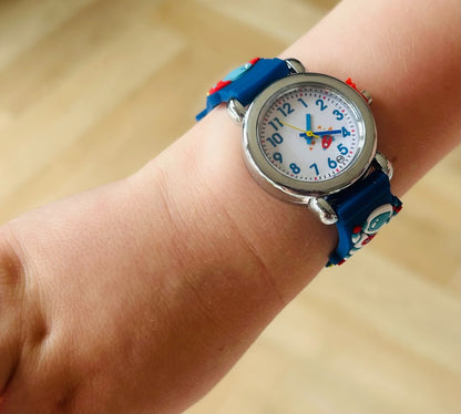 Child's wrist wearing a colorful watch with a blue strap on a wooden surface