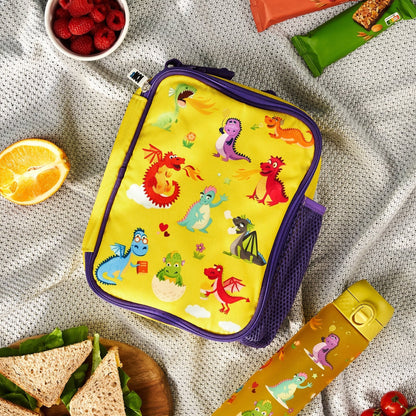 Yellow lunch bag with cartoon designs on a gray textured surface with snacks around